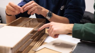 Two Hertfordshire International Students review a model of a designed building