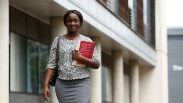 Single female postgraduate student walking on campus at the University of Hertfordshire
