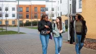 Three female undergraduate students walking together on campus