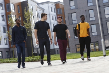 Four male students walking together on campus at the University of Hertfordshire
