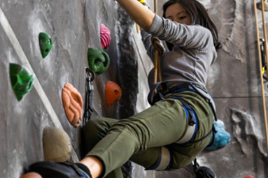 Female rock climber climbing the wall at the Hertfordshire University Sports Village