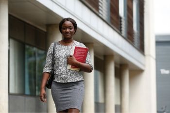 Single female postgraduate student walking on campus at the University of Hertfordshire