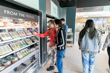 Students picking up food and drink items in the Hertfordshire University campus shop