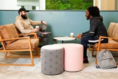Two men sat opposite each other in a seating area talking to each other